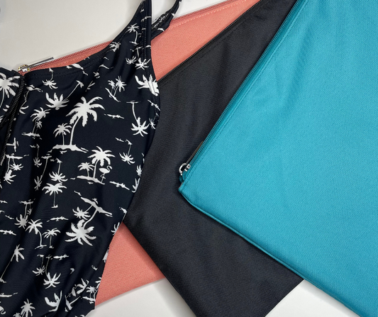 blue, black and pink wet bags on a white background with palm print bathers lying on top