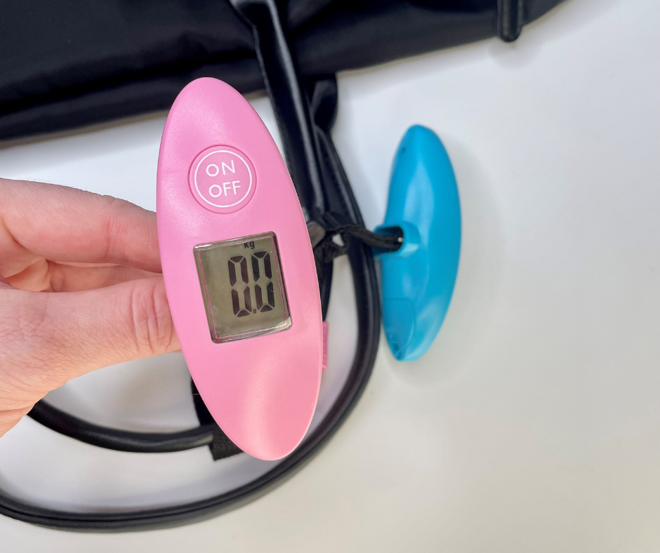 pink luggage tag on a black duffle bag showing a weight on the screen
