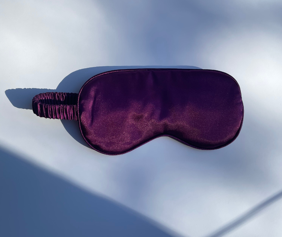 deep purple sleep/eye mask on a white background with sun shining on it
