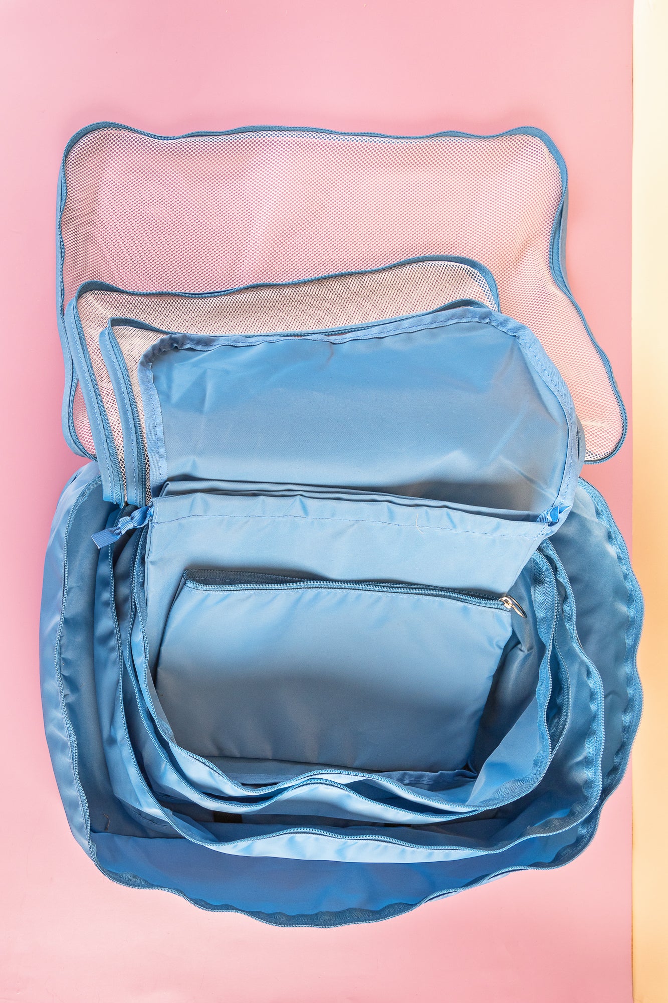 blue packing cubes opened up on a pink and yellow background