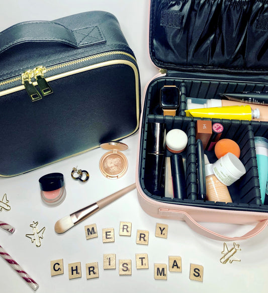 cosmetic cases on a white background with cosmetics spilling out and merry christmas written in scrabble tiles