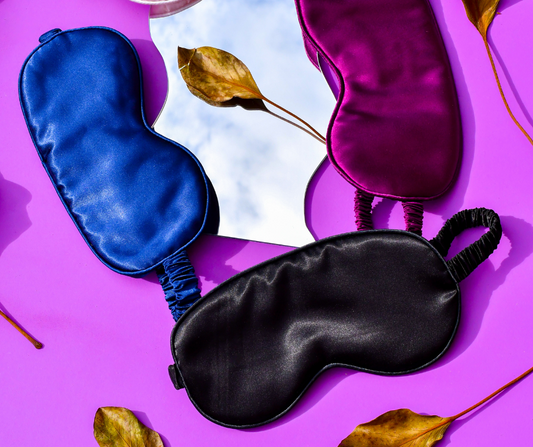 3 x sleep/eye masks on a purple background with a miror and leaves displayed as well