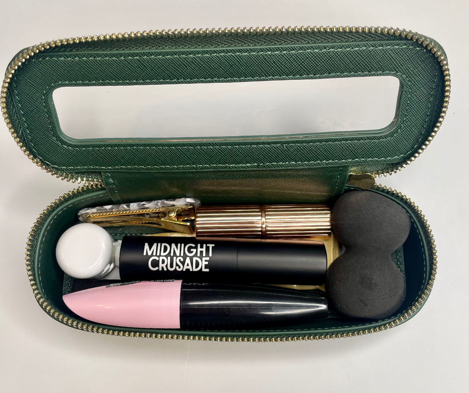 green mini cosmetic case packed with cosmetics on a white background