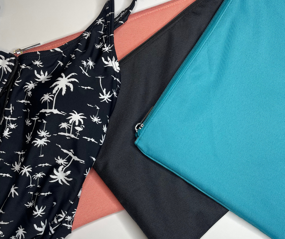 blue, black and pink wet bags on a white background with palm print bathers lying on top