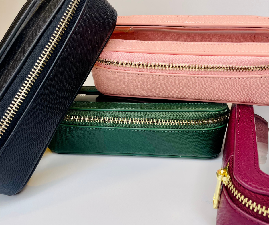 green, pink, purple and black mini cosmetic cases piled on top of each other on a white background