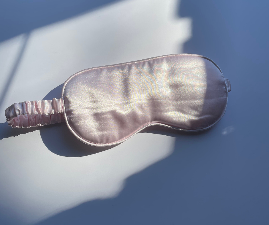 pink eye mask/sleep mask on a white background with the sun shining on it