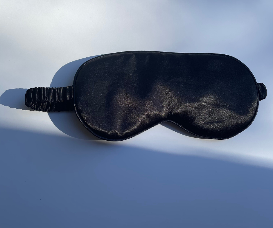 black sleep/eye mask on a white background with sun shining on it