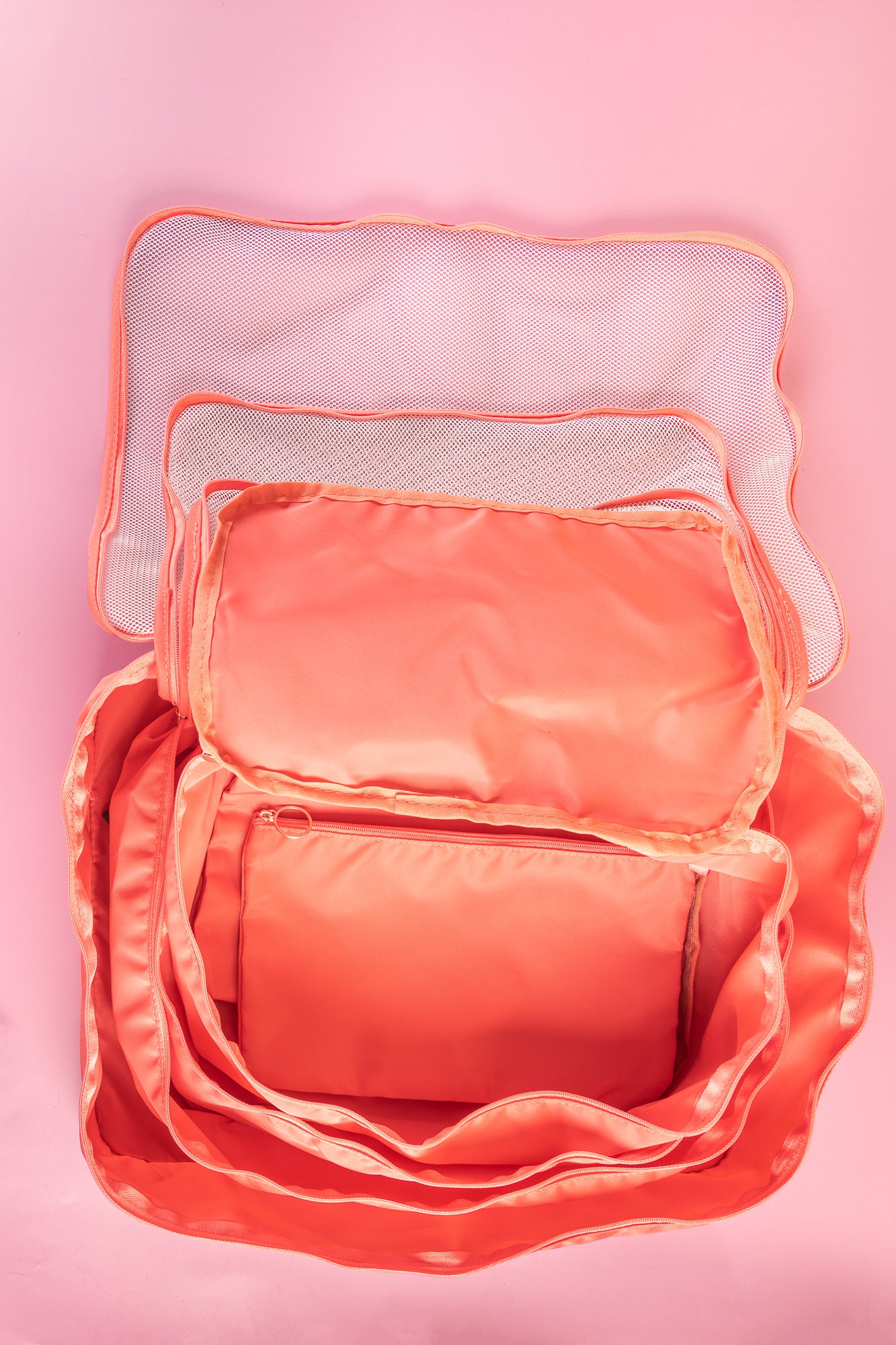 pink packing cubes opened up on a pink background