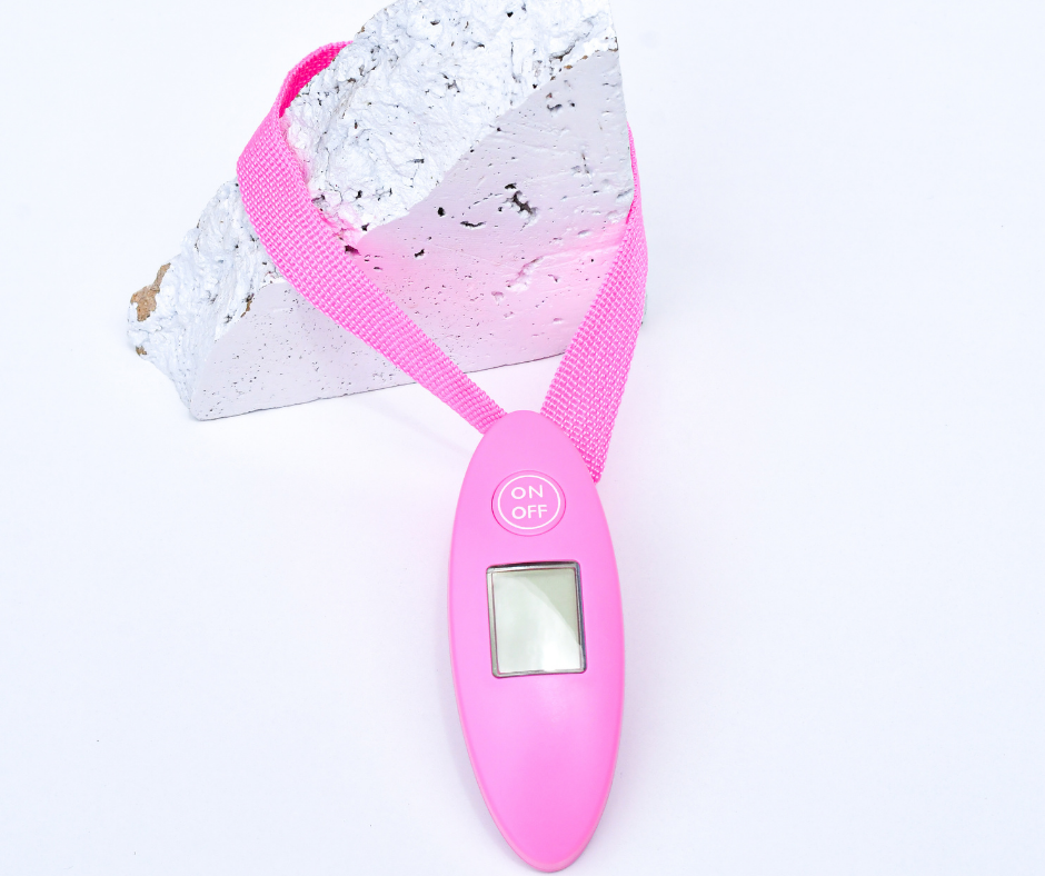pink luggage scales on a white rock on a white background