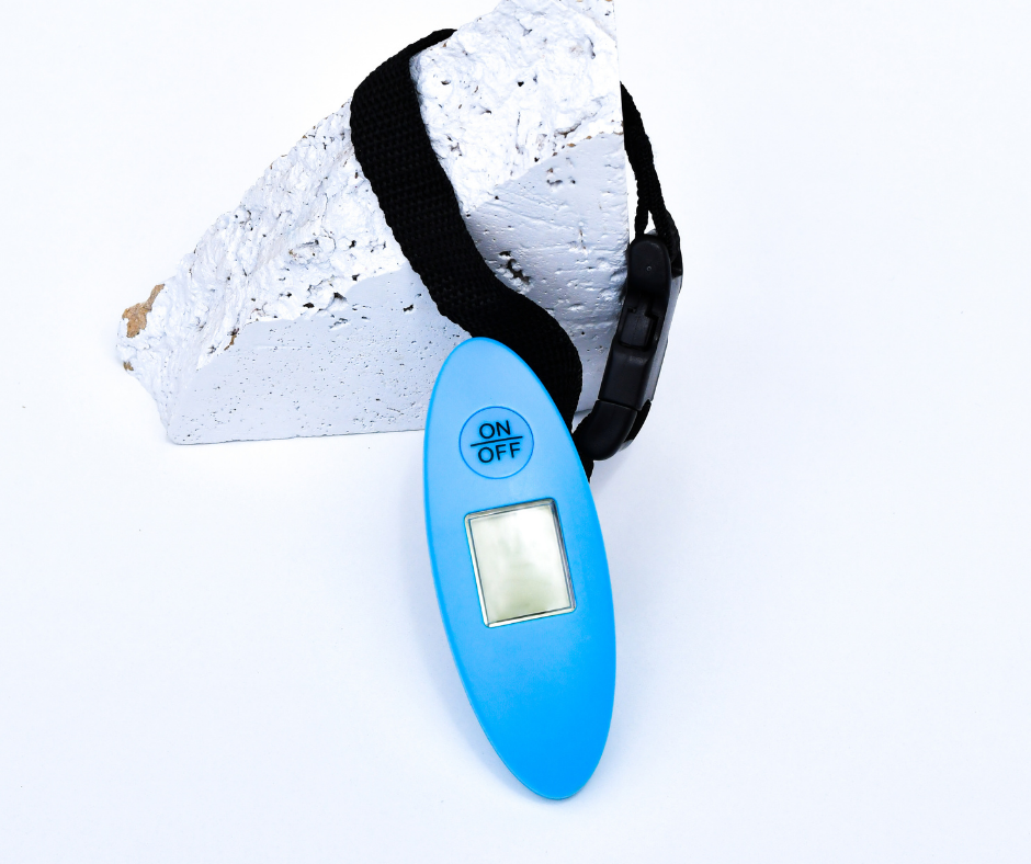 blue luggage scales attached to a white rock on a white background