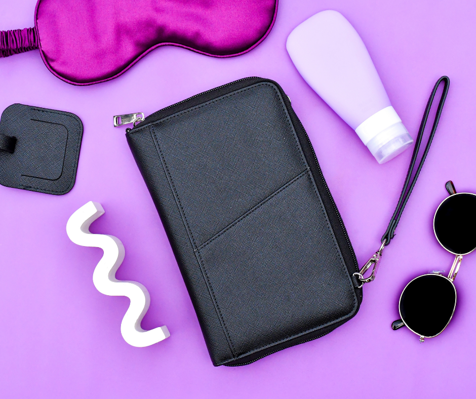 black passport wallet on a purple background with travel essentials laid out next to it