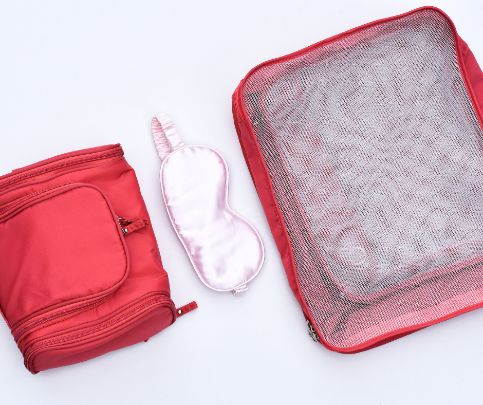 pink cosmetic case, packing cubes and sleep/eye mask on a white/light grey background