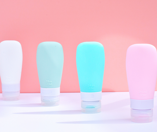 4 travel size bottles (pink, green, blue and white) on a white and pink background